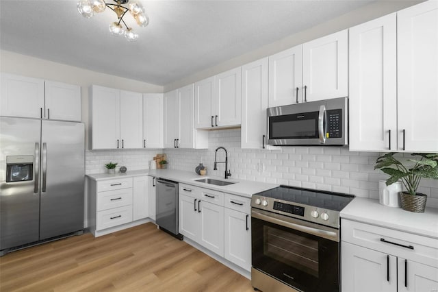 kitchen with a sink, appliances with stainless steel finishes, white cabinets, and light countertops