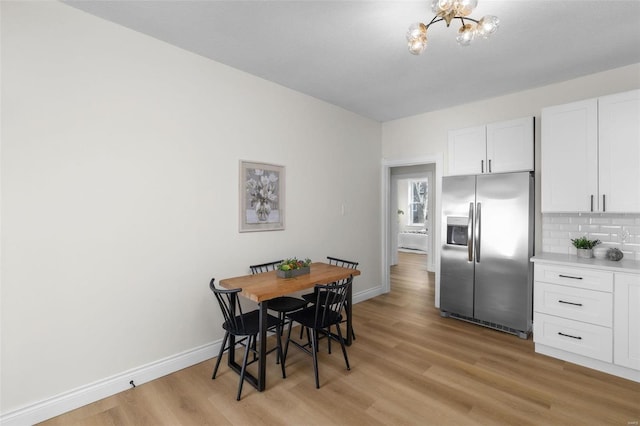 dining room featuring baseboards, an inviting chandelier, and light wood finished floors