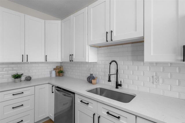 kitchen with light stone counters, a sink, white cabinets, stainless steel dishwasher, and tasteful backsplash