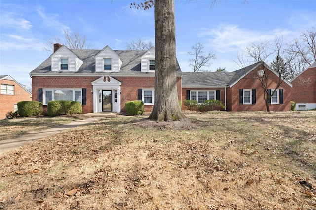 cape cod house with brick siding and a chimney