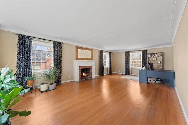 unfurnished living room with baseboards, wood finished floors, a fireplace, and ornamental molding