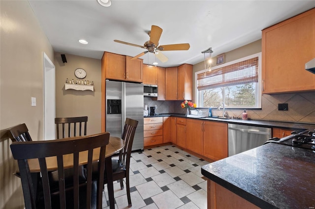 kitchen with dark countertops, tasteful backsplash, ceiling fan, light floors, and appliances with stainless steel finishes