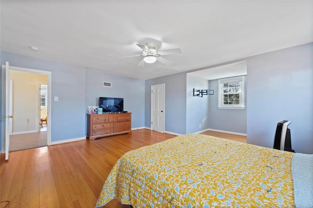 bedroom featuring ceiling fan, visible vents, baseboards, and wood finished floors