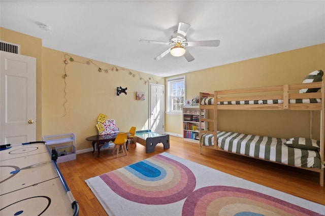 bedroom with ceiling fan, visible vents, baseboards, and wood finished floors