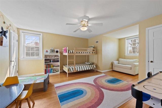 bedroom with visible vents, baseboards, a ceiling fan, and wood finished floors