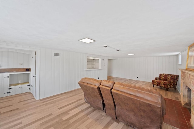 living area with light wood-type flooring, visible vents, and a fireplace