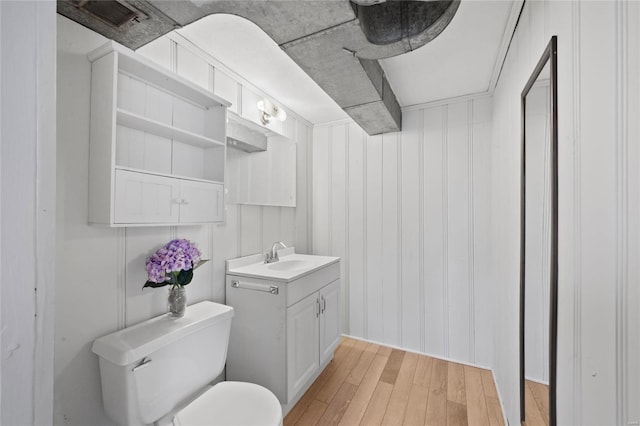 bathroom with toilet, vanity, and wood finished floors