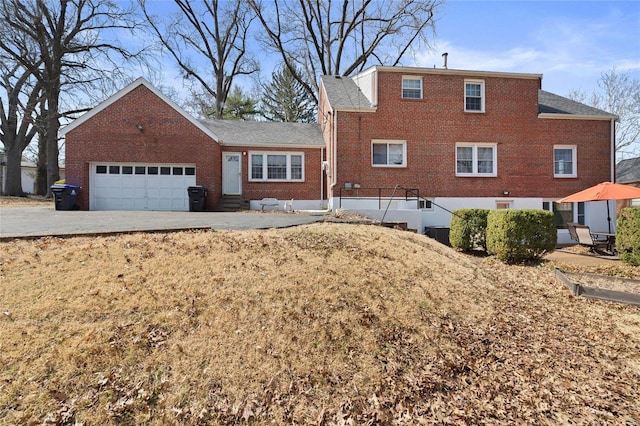 rear view of house with driveway, brick siding, and an attached garage