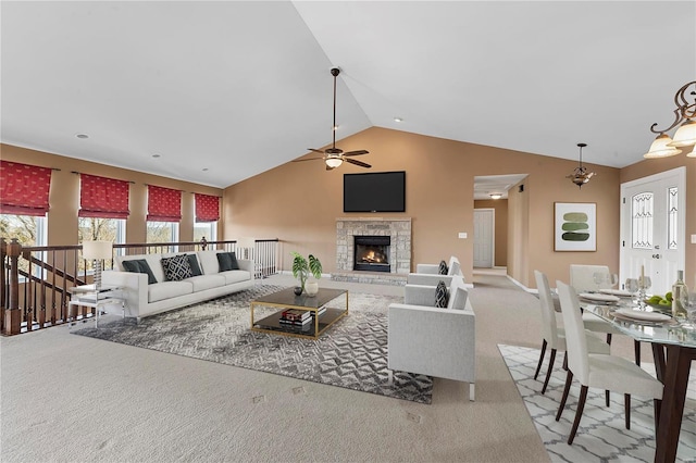 living room featuring high vaulted ceiling, a stone fireplace, ceiling fan, and carpet flooring