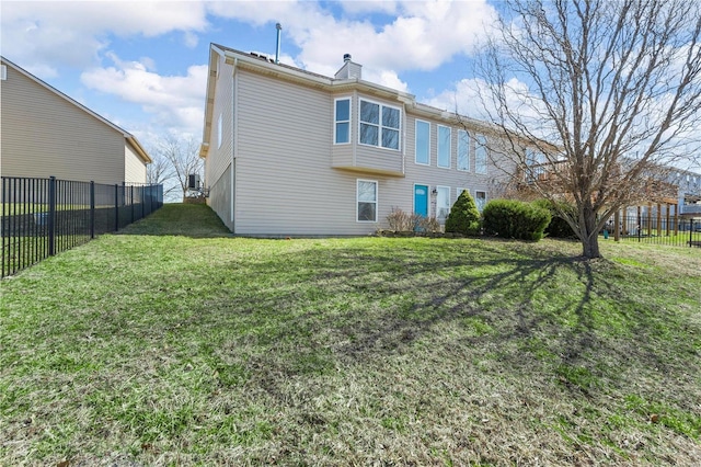 back of property featuring a lawn, a fenced backyard, and a chimney