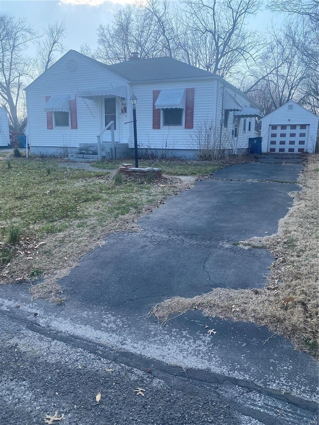 view of front of property featuring a garage, an outdoor structure, and aphalt driveway