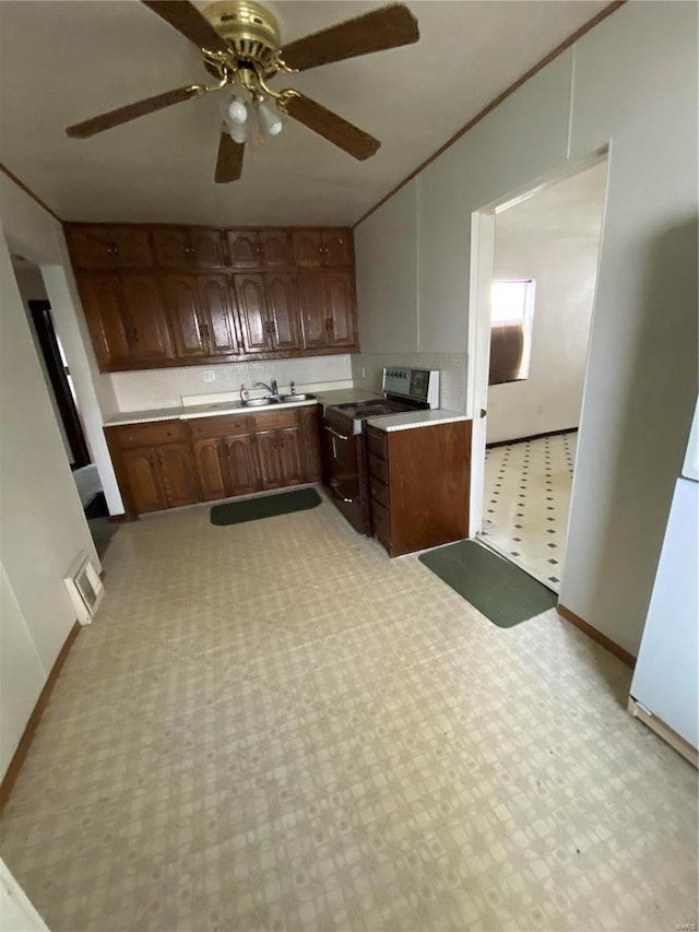 kitchen featuring a ceiling fan, light floors, electric range oven, light countertops, and crown molding