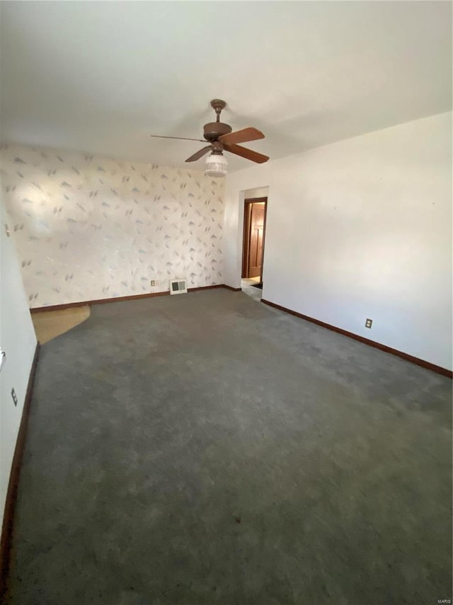 empty room featuring visible vents, wallpapered walls, baseboards, and dark colored carpet