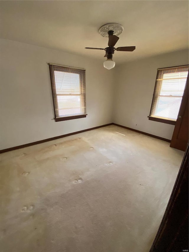 spare room with baseboards, light carpet, and a ceiling fan