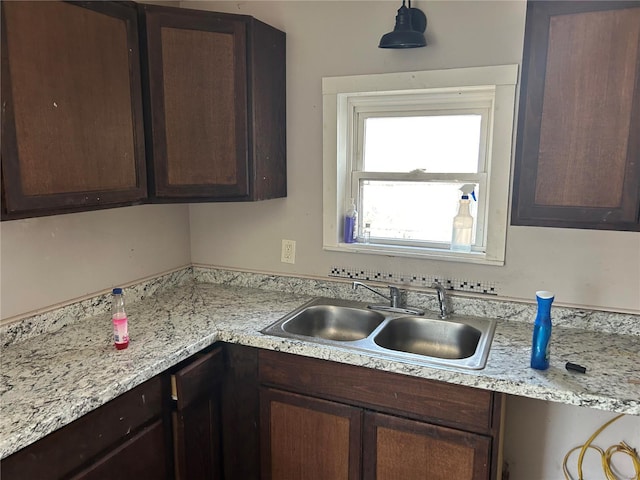 kitchen featuring light countertops, dark brown cabinets, and a sink