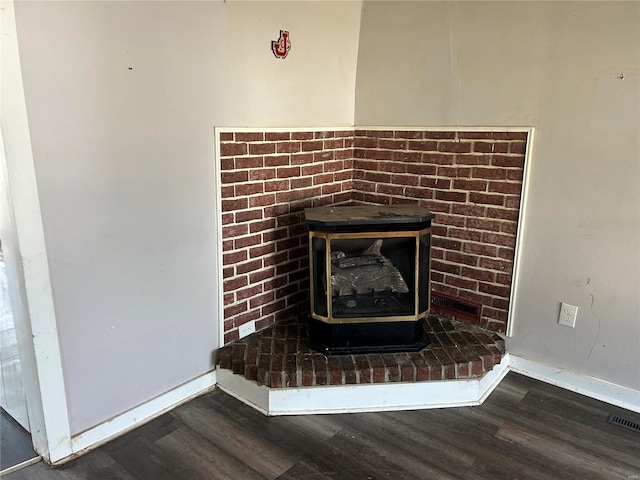 interior details with visible vents, baseboards, wood finished floors, and a wood stove