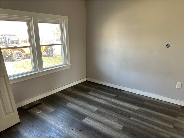 spare room with visible vents, dark wood-type flooring, and baseboards