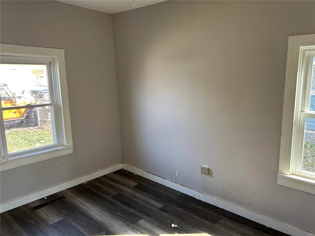 spare room featuring visible vents, baseboards, and dark wood-type flooring