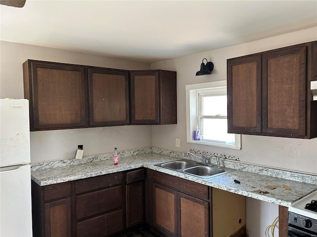 kitchen with a sink, dark brown cabinets, and freestanding refrigerator