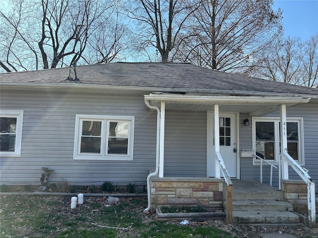 entrance to property featuring a porch and a shingled roof