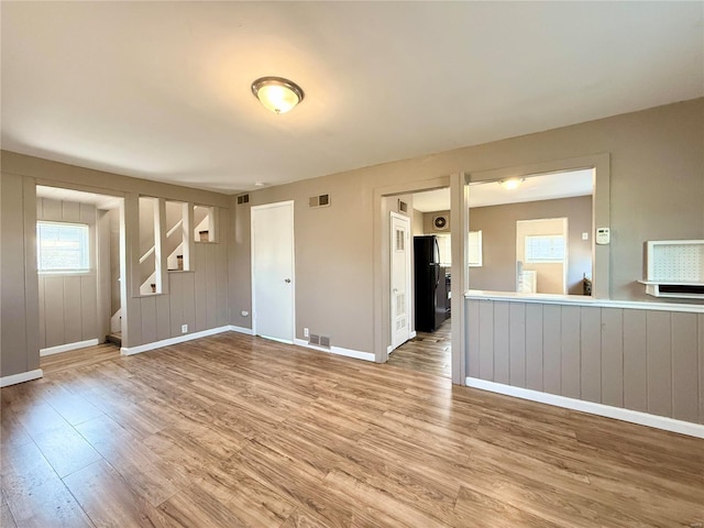 unfurnished living room featuring visible vents, baseboards, and wood finished floors