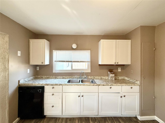 kitchen with white cabinets, light countertops, black dishwasher, and a sink