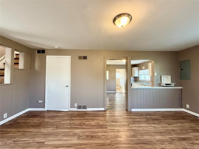 kitchen with electric panel, wood finished floors, and visible vents