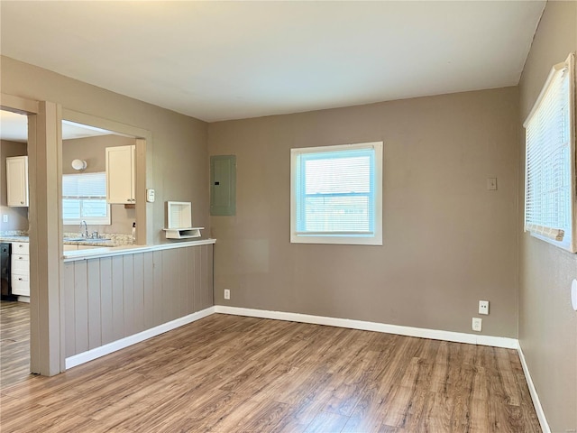 interior space with wood finished floors, baseboards, electric panel, light countertops, and white cabinets