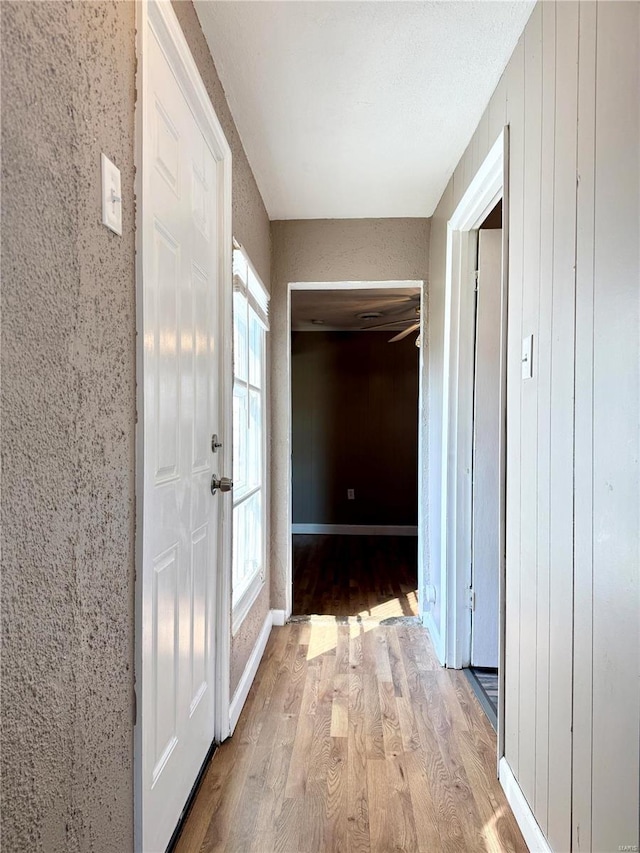 hall with baseboards and wood finished floors