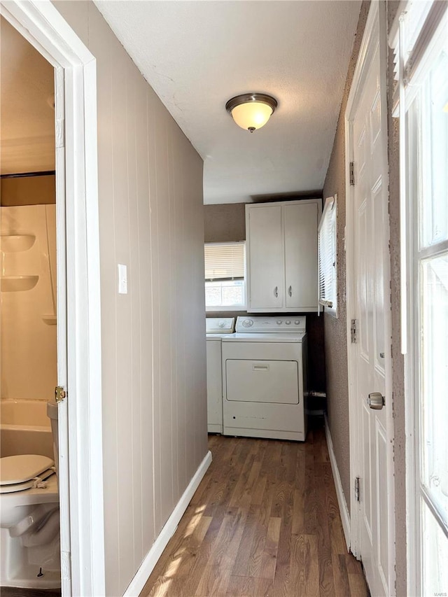 washroom featuring dark wood-type flooring, cabinet space, separate washer and dryer, and baseboards