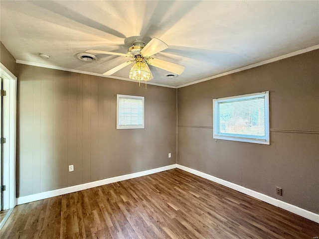 spare room featuring crown molding, wood finished floors, and a wealth of natural light