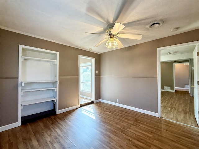 unfurnished bedroom featuring baseboards, wood finished floors, a ceiling fan, and ornamental molding