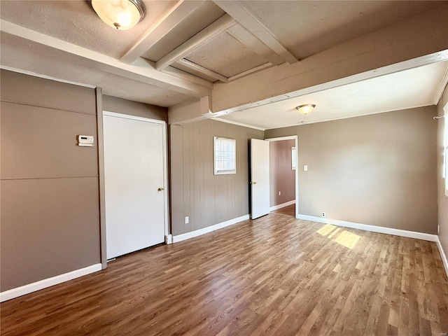 spare room with baseboards and wood finished floors