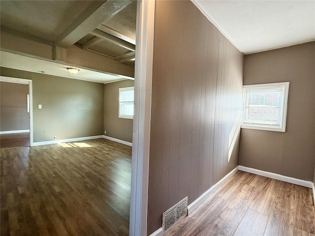 spare room with visible vents, wood walls, baseboards, and wood finished floors