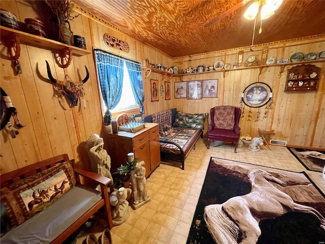 living area featuring visible vents, wooden walls, wooden ceiling, light floors, and ceiling fan