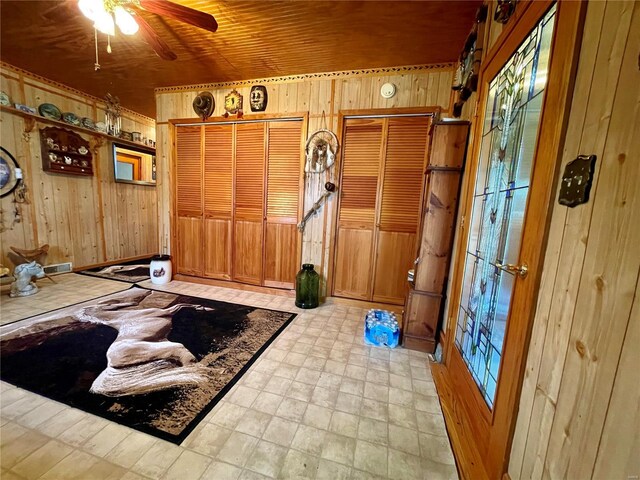 workout area featuring wooden walls, light floors, wood ceiling, and ceiling fan