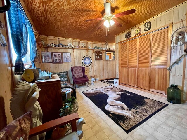 sitting room with tile patterned floors, wood walls, wood ceiling, and ceiling fan