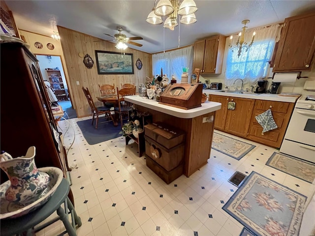 kitchen featuring gas range gas stove, light floors, light countertops, brown cabinets, and a sink