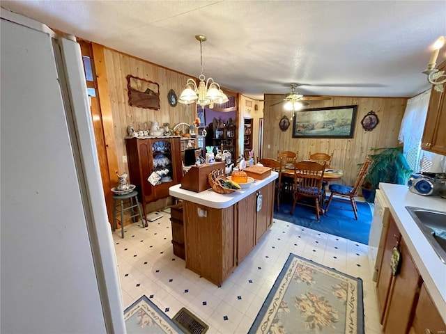 kitchen featuring decorative light fixtures, light floors, light countertops, brown cabinetry, and a sink