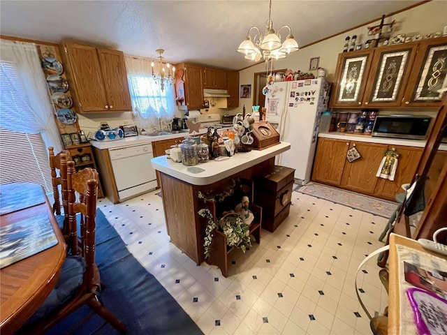 kitchen with a notable chandelier, under cabinet range hood, white appliances, light countertops, and light floors