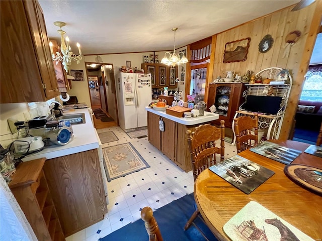 kitchen with light floors, a sink, light countertops, white refrigerator with ice dispenser, and a notable chandelier