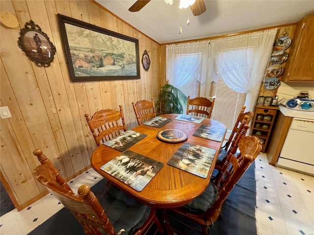 dining area with wooden walls, light floors, a ceiling fan, and lofted ceiling