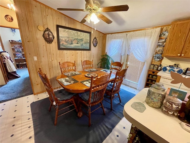 dining room featuring tile patterned floors, wood walls, and ceiling fan