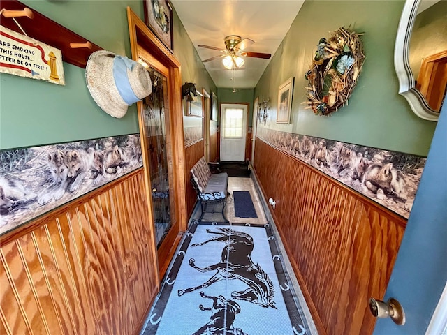 entryway with a wainscoted wall, wooden walls, and a ceiling fan