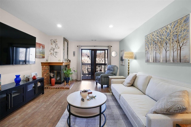 living area featuring recessed lighting, a brick fireplace, and wood finished floors