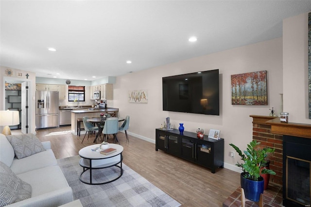 living area with recessed lighting, a fireplace, baseboards, and light wood finished floors