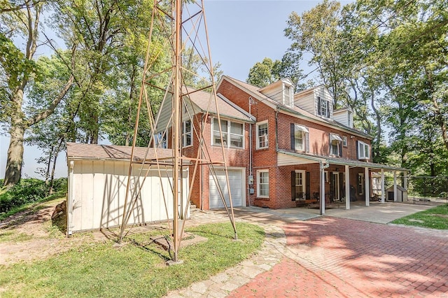 rear view of house featuring a garage, decorative driveway, and brick siding