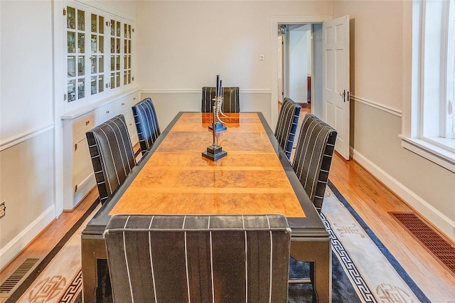 dining area featuring visible vents, baseboards, and wood finished floors