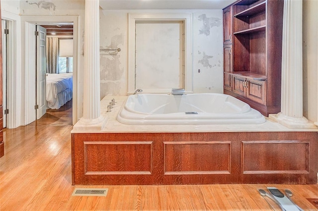 bathroom with visible vents, a garden tub, decorative columns, wood finished floors, and ensuite bath