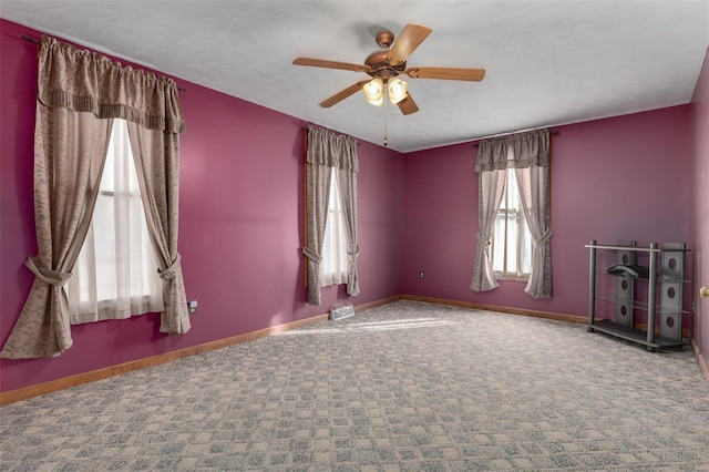 carpeted spare room with ceiling fan, a textured ceiling, and baseboards